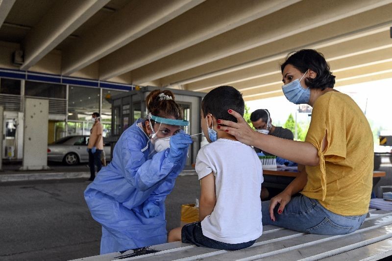 A health worker wearing protective gear takes swab samples from tourists to test for the coronavirus, at Promahonas border crossing with Bulgaria, which is the only land border into Greece that is open. (Photo by Giannis Papanikos/AP Photo)